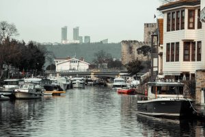 Beautiful canal in Beykoz, İstanbul with boats, historic buildings, and urban skyline in the background.